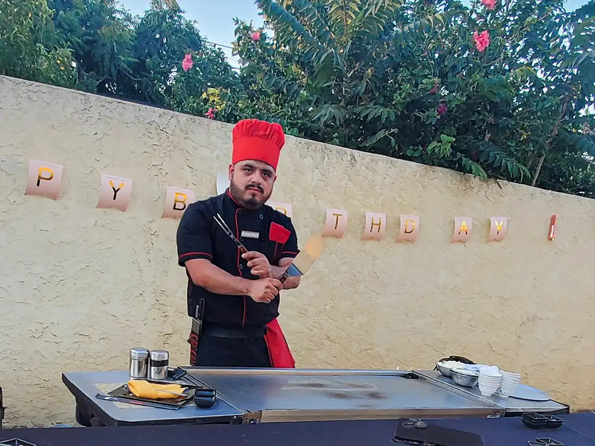 Hibachi chef performing a flaming show in front of guests outdoors